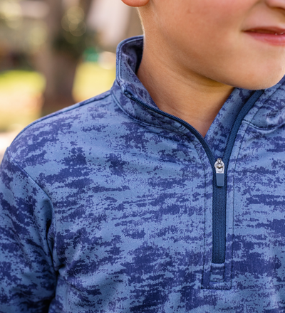 A young boy modeling a Turtles and Tees blue patterned golf pullover