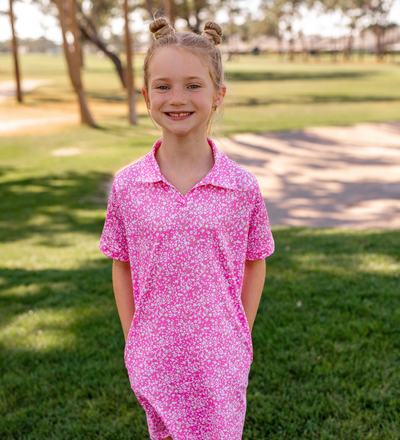 A young girl modeling a Turtles and Tees pink and white floral golf dress
