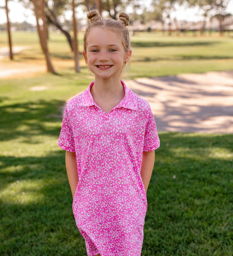 A young girl modeling a Turtles and Tees pink and white floral golf dress