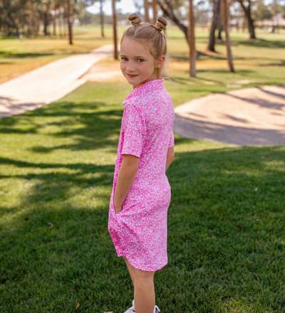 A young girl modeling a Turtles and Tees pink and white floral golf dress