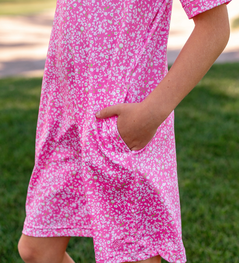 A young girl modeling a Turtles and Tees pink and white floral golf dress