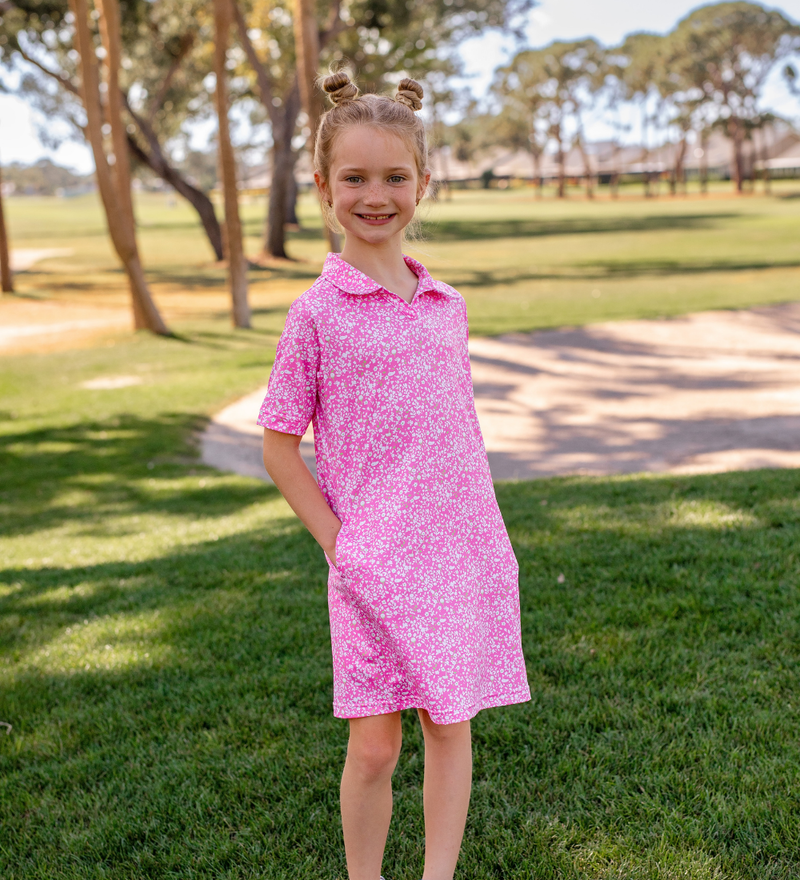 A young girl modeling a Turtles and Tees pink and white floral golf dress