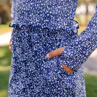 Person wearing a Turtles and Tees blue floral dress with a blurred outdoor background
