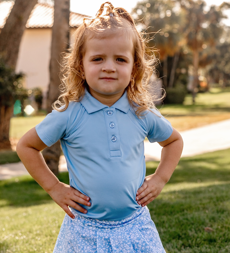 A toddler girl modeling a Turtles and Tees girls blue golf polo and blue floral girls skort