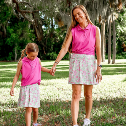 A woman and daughter wear matching mommy and me pink polos and pink and green floral skorts